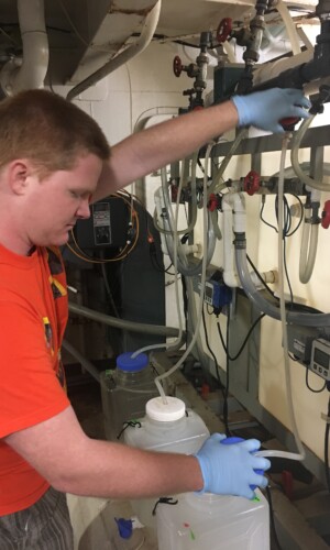 Graduate student, Sean Fitch, checks flow rates for each replicated carboy.