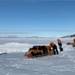 Crew pushing our gear on sleds with Mt. Discovery in the background
