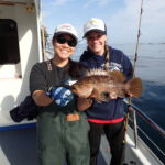 Jen C. and Holly C. showing off a Kelp Rockfish (Sebastes atrovirens) Jen C. and Holly C. with a kelp rockfish on a CCFRP trip