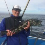 Volunteer angler Dave K. showing off a Lingcod (Ophiodon elongatus) on the bow of the F/V Huli Cat Volunteer angler Dave K. showing off a Lingcod (Ophiodon elongatus) on the bow of the F/V Huli Cat