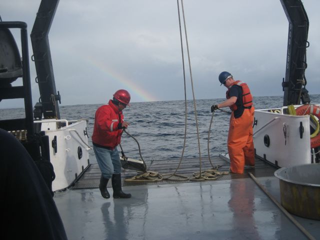 The crew hauls in the net, while a rainbow offsets the less-than-ideal weather (photo: E. Loury)