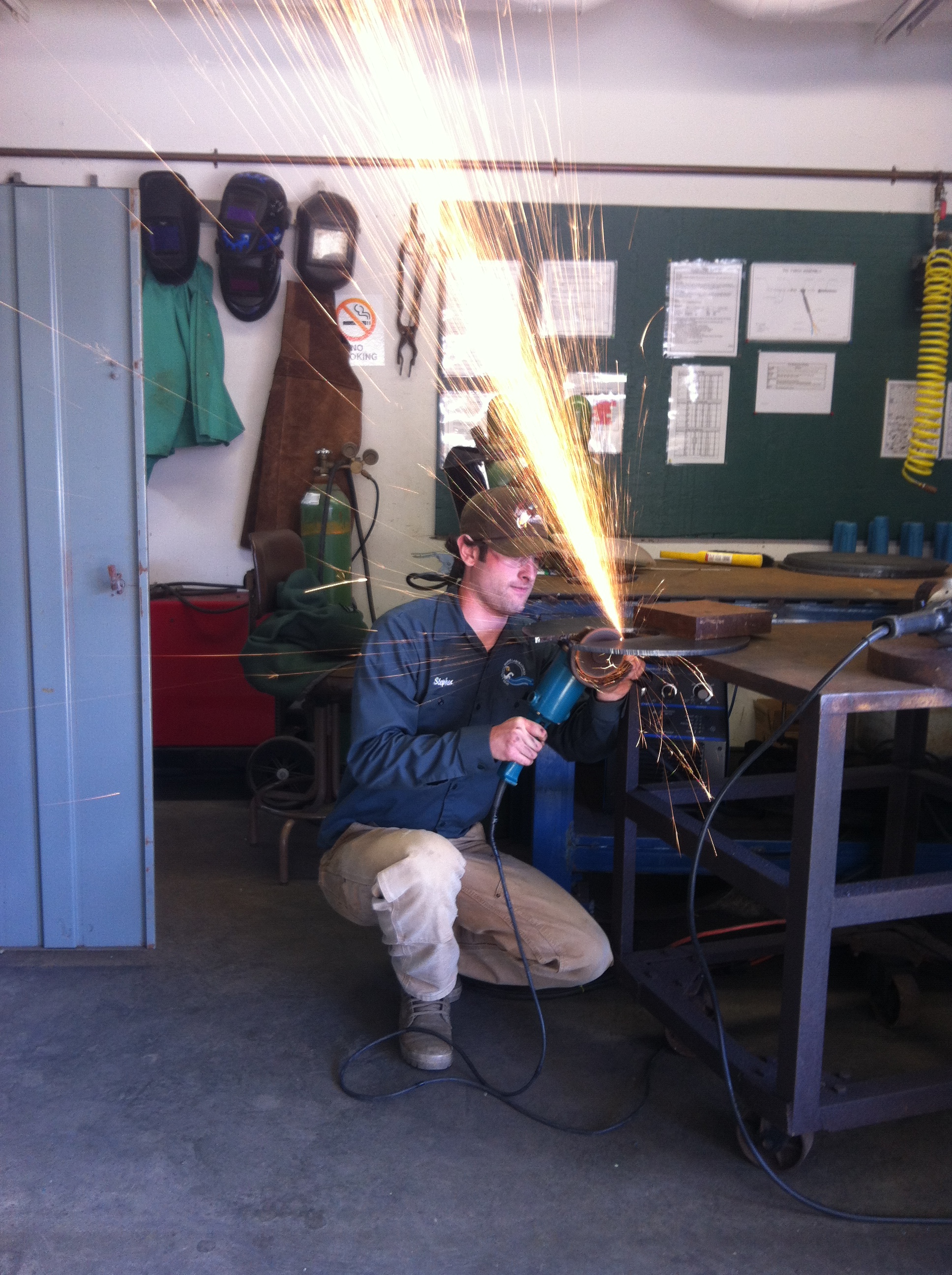 Stephen Loiacono uses a portable grinder to shape the top plate of the tripod. Photo by: Catherine Drake.