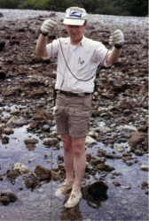 Dr. Nybakken in "full field trip mode", with forceps on cord around his neck, field notebook on right hip, thermometer and Rapidograph pen in shirt pocket. Holding large Nemertean at Cruz Huanacaxtle, Nayarit, Mexico, 23 Jan 1975. Photo by Gary McDonald.