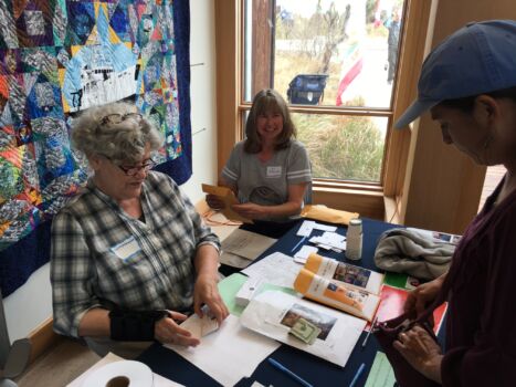 Lynn McMasters and Lois DeVogelaere sell raffle tickets for the three quilts,, the R/V Point Sur quilt is in the background. I think that is Sal Cerchio on the right coughing up some dough.